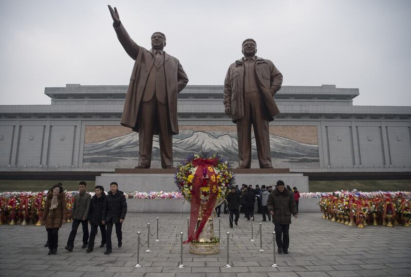 North Koreans walk before statues of former presidents Kim Il-Sung (L) and Kim Jong-Il (R) at the Mansudae Grand Monument on New Year's Day in Pyongyang on January 1, 2017.