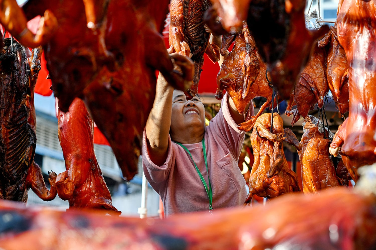 Ein Verkäufer hängt am 28. Januar 2025 ein geröstetes Schwein zum Verkauf auf einem Markt in Phnom Penh.