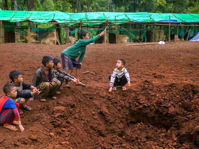 Boys play at a bomb site after an aerial attack on a refugee camp in Western Dim So, Kayah State, Myanmar,  June 4, 2023.