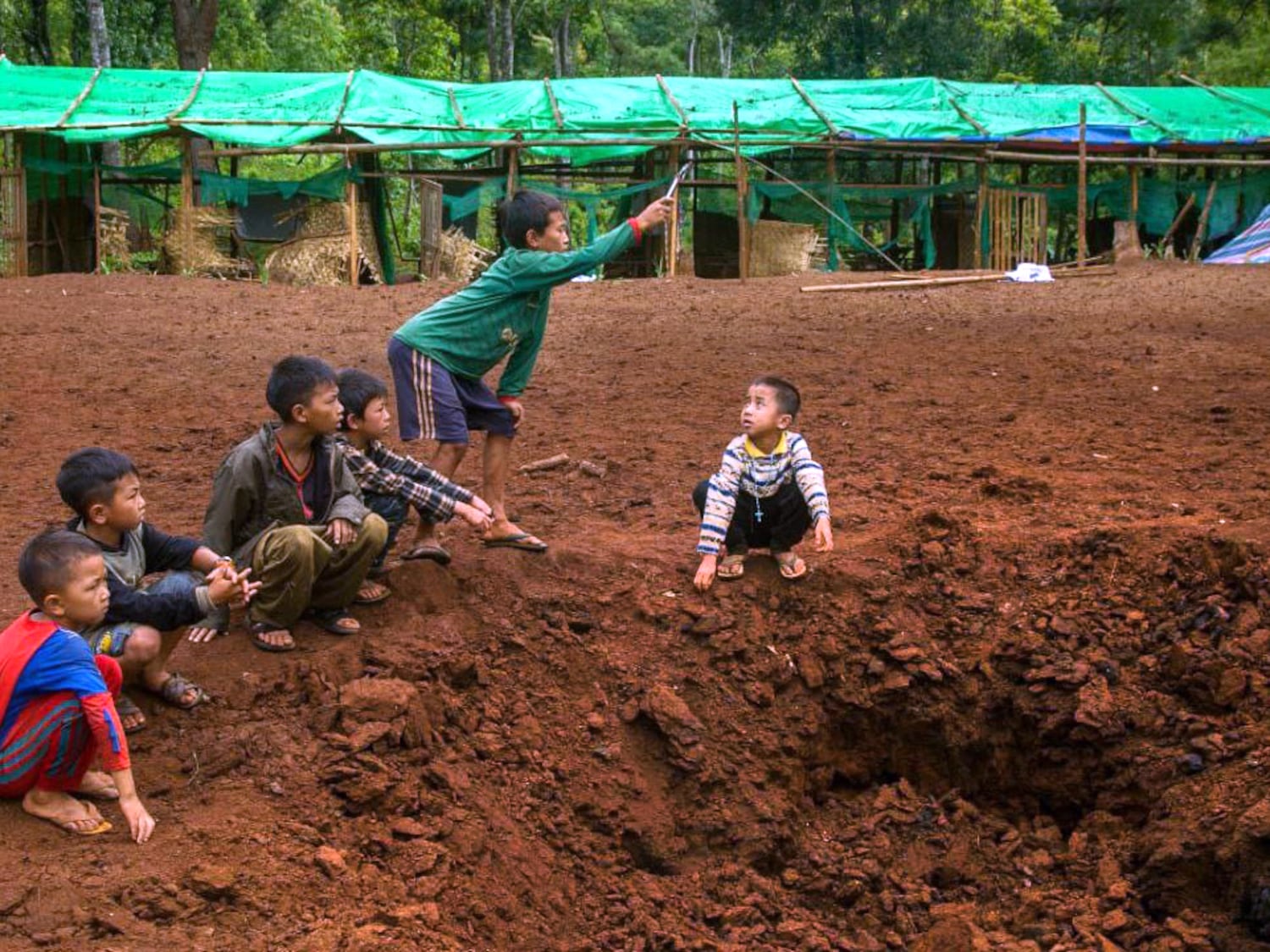 Boys play at a bomb site after an aerial attack on a refugee camp in Western Dim So, Kayah State, Myanmar,  June 4, 2023.