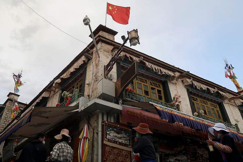 大昭寺附近街道上，一面中国国旗在监控摄像头上方飘扬。（路透社）