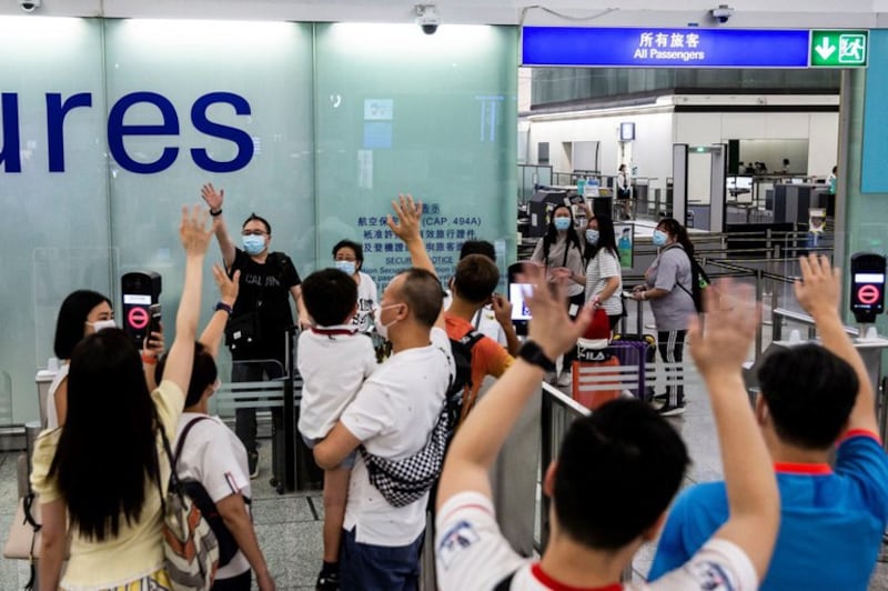 People waving goodbye as a family makes their way through the departure gates of Hong Kong's International Airport, July 22, 2021. Credit: AFP