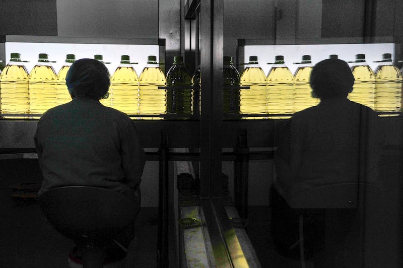 An employee (L) is reflected as she works at the production line of an edible oil company in Sanhe, Hebei, April 12, 2011. (Reuters)