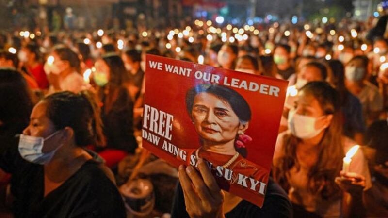 A Myanmar protester holds a poster with an image of detained civilian leader Aung San Suu Kyi during a candlelight vigil to honor those who have died during demonstrations against the military coup, in Yangon, March 13, 2021. AFP