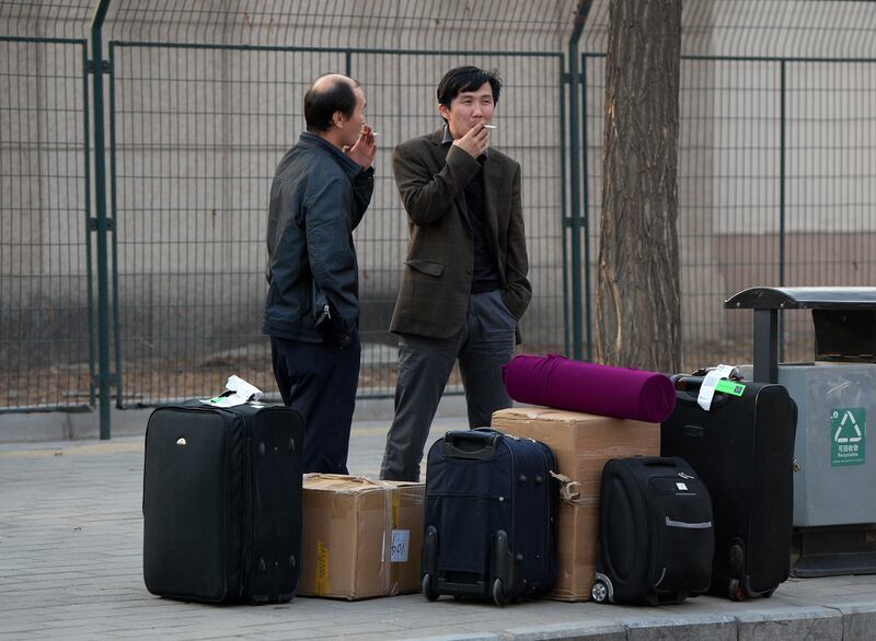 Two North Korean men stand beside suitcases as they wait for transport outside the North Korean embassy in Beijing on April 4, 2013. AFP PHOTO_Mark RALSTON 000_Hkg8447860.jpg