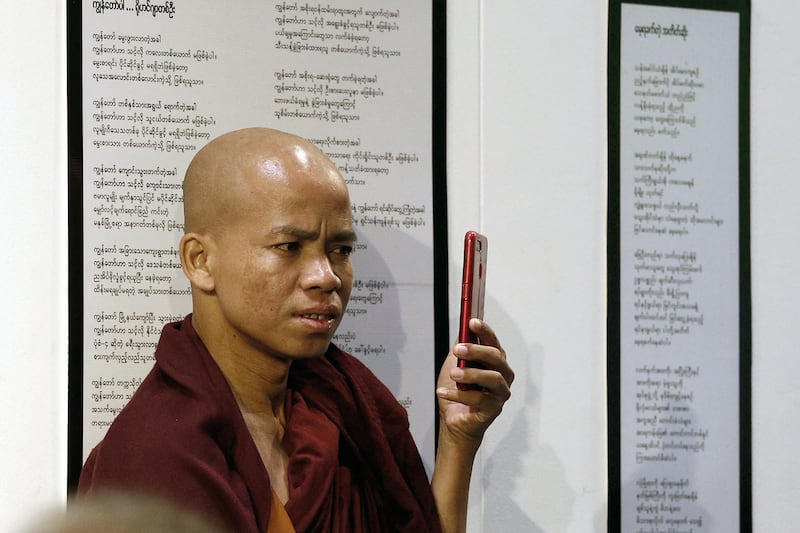 A Buddhist monk records a video with his mobile phone as he listens to Rohingya Muslim poets during the "Poetry for Humanity" event in Yangon, Myanmar.