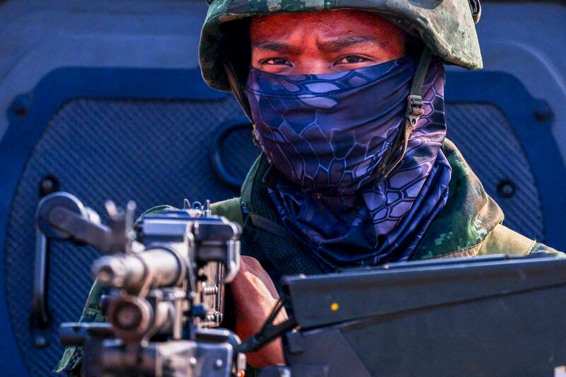 A soldier stands guard as hundreds of refugees cross over the Moei River frontier between Myanmar and Thailand in Mae Sot, Tak province, Thailand, April 13, 2024. (Athit Perawongmetha/Reuters)