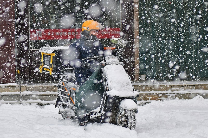 2023年12月20日，山东烟台，一名外卖骑手在雪中行驶。（法新社）