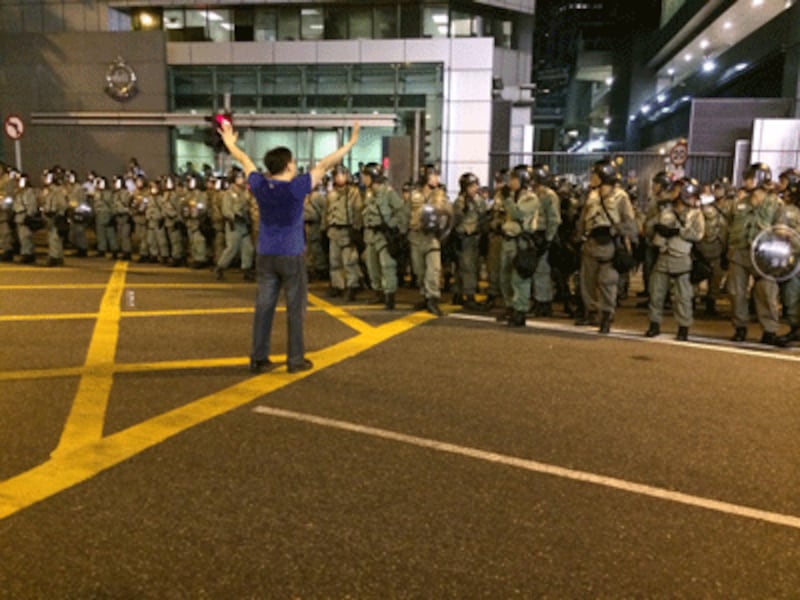 A protester raises his hands in front of riot police.(RFA photo)