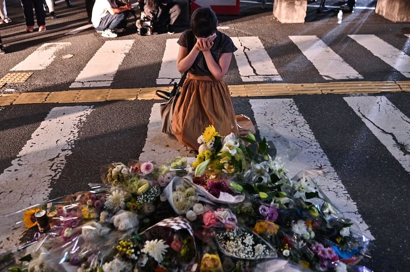 A woman reacts in front of a makeshift memorial outside Yamato-Saidaiji railway station in Nara, Japan, where former Japanese Prime Minister Shinzo Abe was shot earlier in the day on July 8, 2022. (AFP)