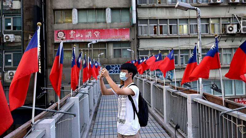 2021 年 10 月 7 日，台湾台北即将举行的国庆庆祝活动之前，一名男子在装饰有台湾国旗的立交桥上拍照。（路透社）