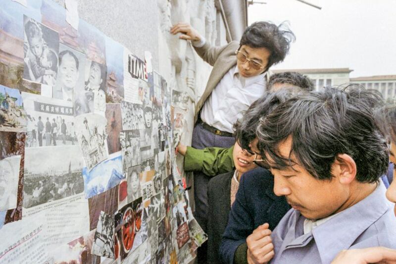 1989年4月21日，人群聚集在天安门广场人民英雄纪念碑底座前，观看从外国杂志上剪下来的前中共总书记胡耀邦的照片。胡耀邦于4月15日去世，引发了前所未有的民主示威浪潮。（亨丽埃特/法新社）