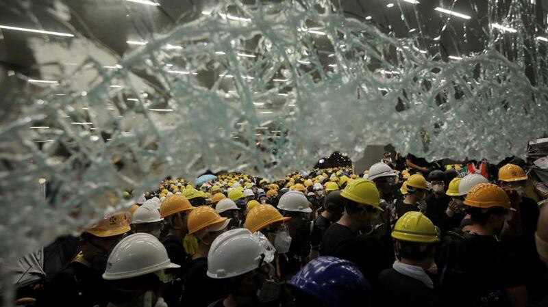 Protesters gather below a smashed window at the government headquarters in Hong Kong, July 1, 2019, the 22nd anniversary of the city's handover from Britain to China.