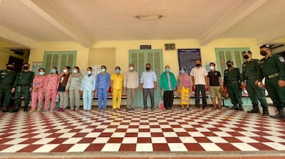 Police pose with 13 people facing charges related to the alcohol poisoning death of a dozen people in Kandal province, May 23, 2021. Kandal Provincial Police Department Facebook page